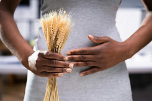 Celiac Disease And Gluten Intolerance. Women Holding Spikelet Of Wheat